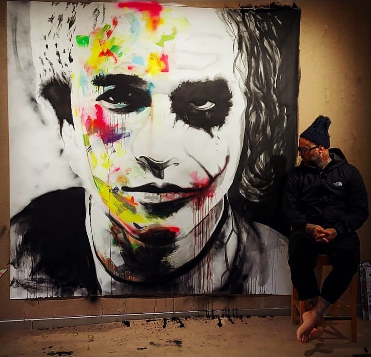 Max White in his studio beside a colour portrait of the Joker