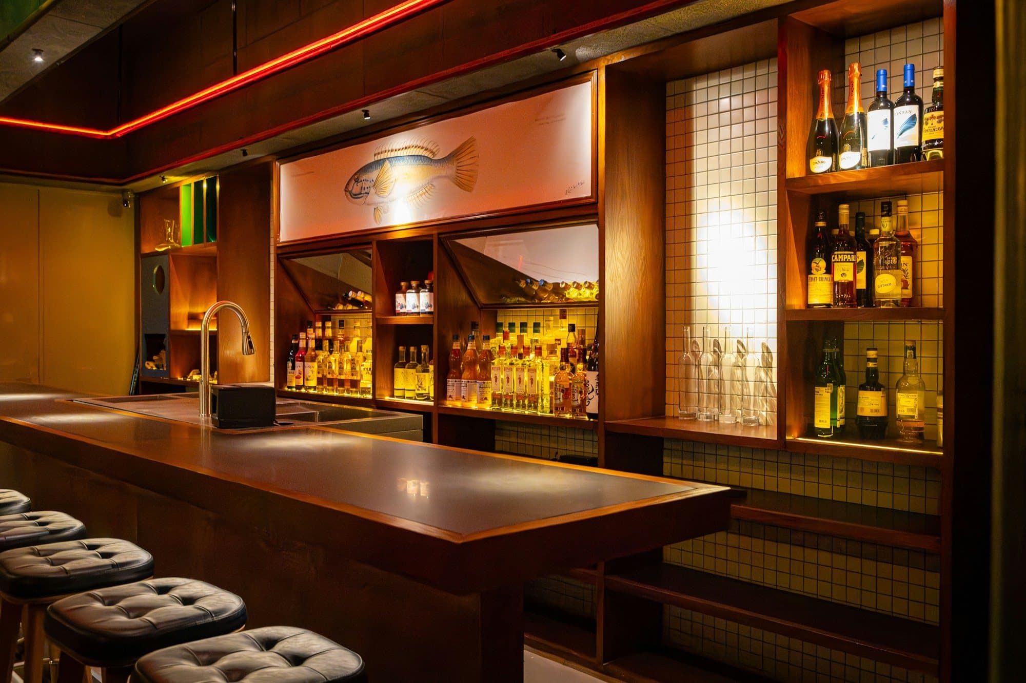 A dimly lit cocktail bar with leather stools