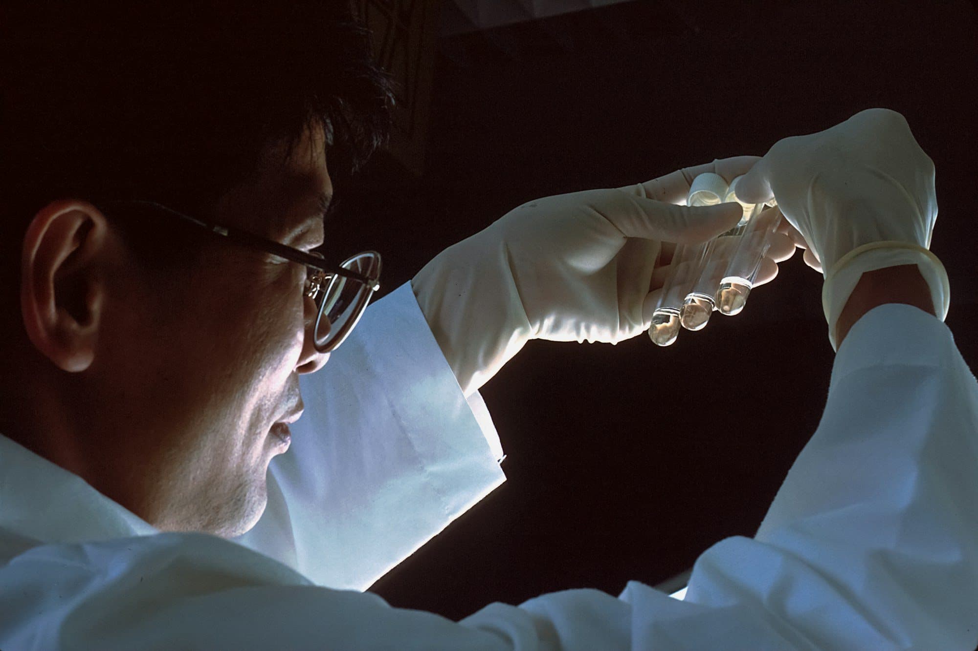A scientist holding vials up to the light